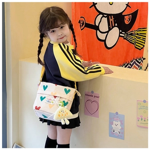 Détail d'un sac bandoulière enfant en toile avec motifs cœurs colorés et un pendentif mignon