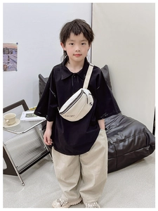 Détail d'un enfant portant un sac bandoulière blanc avec inscription KAYINAI