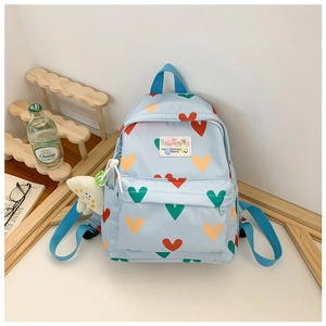 Détail d'un sac à dos bleu clair en nylon à motifs cœurs avec un porte-clé poulpe en peluche