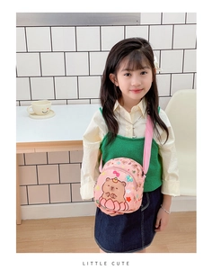 Pink cartoon bear crossbody bag with adjustable strap worn by a young girl in a studio