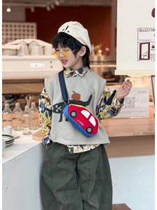 Close-up of a child wearing a red car-shaped crossbody bag with adjustable black strap