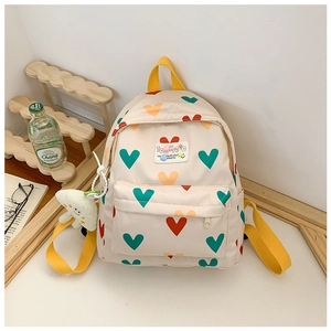 Détail d'un sac à dos beige à motif cœurs, bretelles jaunes et charme nuage en peluche