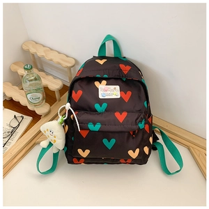 Détail du sac à dos enfant avec motifs de cœurs colorés et un porte-clé peluche blanc