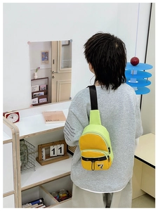 Détail du sac de poitrine bicolore jaune et vert pour enfants porté par un modèle