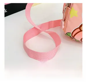 Detail of pink adjustable woven strap and cartoon peach zipper on kid's shoulder bag