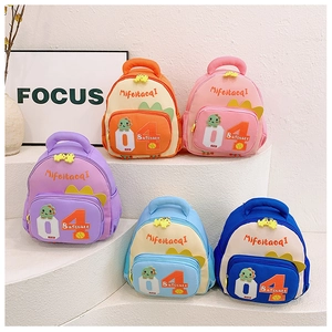Reihe bunter Kinderrucksäcke mit Dino-Motiven in Orange, Rosa, Lila und Blau