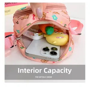 Interior storage view of a pink cartoon bear crossbody bag showing items for kids