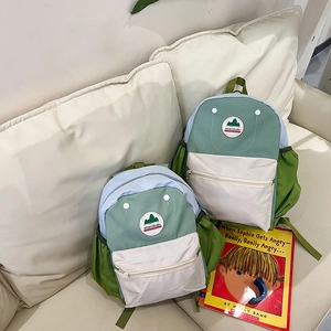 Detailed set of two stylish kids backpacks in green and blue on a cozy fabric sofa