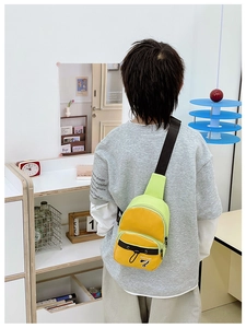 Vue arrière d'un enfant portant un sac de poitrine croisé vert néon et jaune avec sangle noire