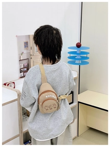 Rear view of a child wearing a beige crossbody bag with adjustable straps in a modern room