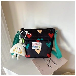 Détail du sac bandoulière en toile avec motifs cœurs et pendentif nuage peluche