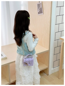 Detailed view of the cute purple cartoon bear print and gold chain strap on the child bag