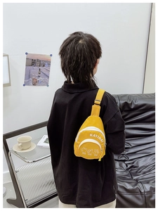 Close-up of bright yellow nylon chest bag for kids with letter print and adjustable strap