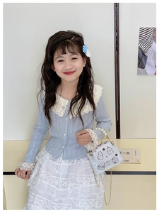 Detail of child wearing a blue knit cardigan with lace collar and pearl chain purse