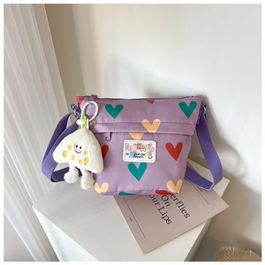 Détail du sac à bandoulière enfant violet en toile avec imprimés cœurs et breloque
