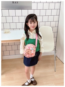 Detailed view of pink cartoon capybara crossbody bag worn by a young child model