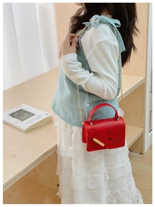 Detail of red cartoon girl's handbag with gold chain strap and cute character print