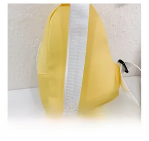 Detail showing the adjustable wide white fabric strap on a bright yellow kids crossbody bag