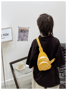 Detail of a bright yellow mini nylon chest bag for kids with hand gesture prints