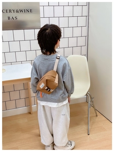 Vue arrière d'un enfant portant le sac de poitrine en toile marron avec sangle réglable