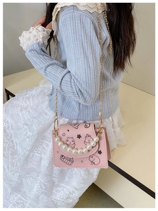 Pink girl's crossbody bag with pearl handle and cartoon capybara print shown on model