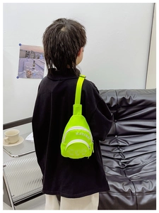Detail of neon green kids chest bag with white Kayinai lettering and zipper pockets