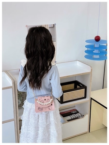 Pink girl shoulder bag with pearl handle and cartoon patterns shown on a model back view