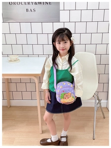 Kids purple crossbody bag with cartoon bear print shown on a young model outdoors