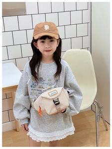 Détail de sac de poitrine enfant avec fermeture orange et patch logo en toile