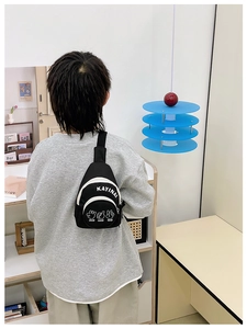 Rear view of a child wearing a casual black canvas chest bag with white letter prints