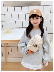 Détail de sac banane enfant beige avec logo en cuir marron et cordon de serrage orange