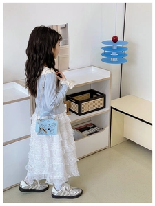Girl wearing light blue lace top, white cake skirt, and cartoon bear chain shoulder bag