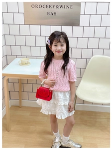 Pink knit top and ruffled skirt outfit for girls paired with a cartoon mini handbag