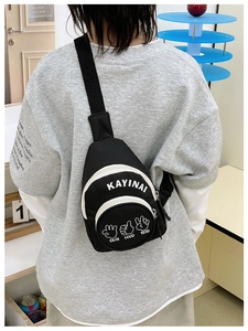 Detail showing black canvas kids chest bag with letter prints and gesture patterns