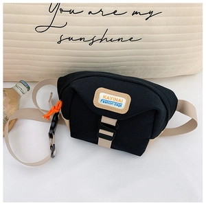 Détail du sac de poitrine en toile avec écusson de marque et zip orange vif