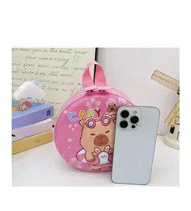 Pink hard shell Capybara toddler bag shown next to a smartphone for size reference