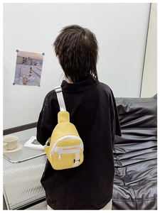 Detailed macro view of yellow nylon kid's chest bag with white adjustable straps and buckle