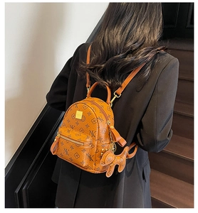 Brown mini backpack featuring floral monogram print and a cute dog pendant on model