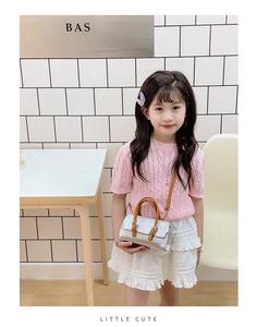Silver kids handbag with brown handles worn by a child model in a lifestyle scene