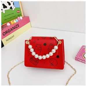 Detail of red kids crossbody bag with cartoon capybara print and pearl handle