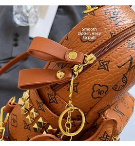 Close-up of smooth gold metal zipper and rivet details on monogram leather backpack