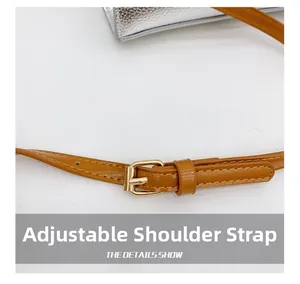 Detail of silver pebble grain leather bag with adjustable tan shoulder strap and gold buckle
