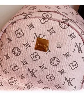 Macro detail of pink lychee leather backpack with monogram pattern and gold brand plate