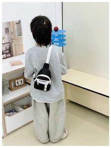 Rear view of a child wearing a black and white fashion crossbody bag with letter print
