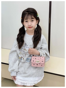 Dettaglio della mini borsa rosa con manico di perle e chiusura su outfit bimba
