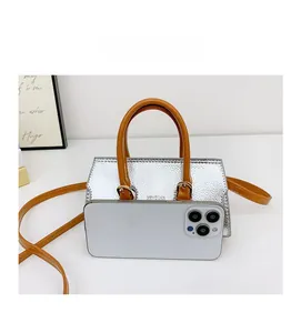 Mini silver metallic kids handbag shown next to a smartphone for size comparison