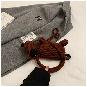 Detailed close-up of handmade brown knitted puppy bag on stylish winter outerwear