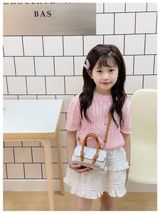 Silver metallic child handbag with brown leather strap detail shown in a lifestyle setting
