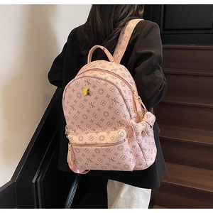 Detail of pink faux leather backpack with monogram pattern and gold logo on model