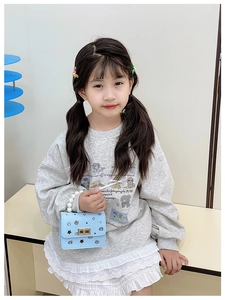 Dettaglio della borsa azzurra da bambina con manico di perle e fibbia su una modella